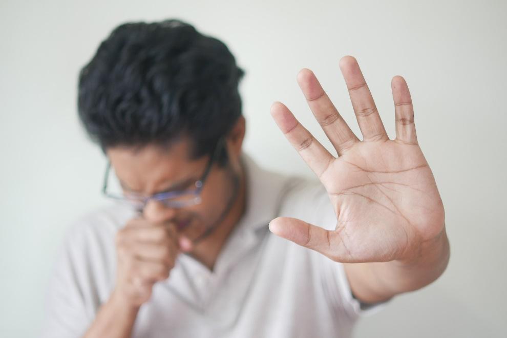 Man with black hair coughing 